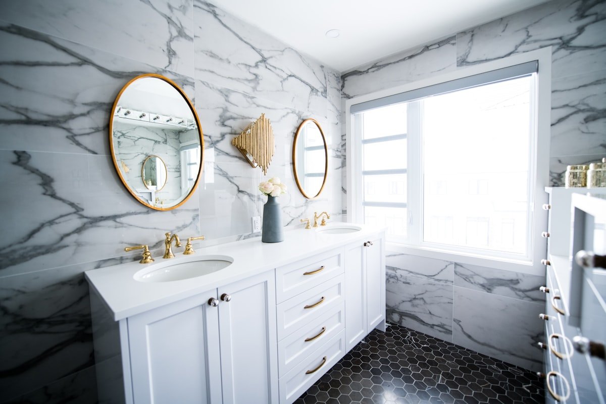 Bathroom with marble walls, double vanity and brass fixtures